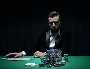 Ärgerlicher Mann im Smoking sitzt vor einem Pokertisch